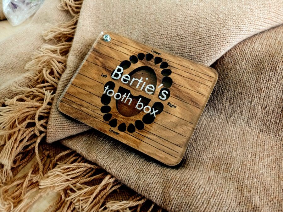 a wooden baby tooth box with a glass lid
